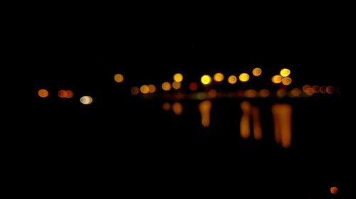 Defocused image of illuminated lights against sky at night