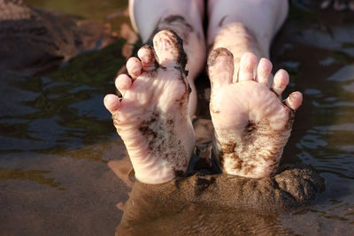 Bare feet of a child on a river in the sand