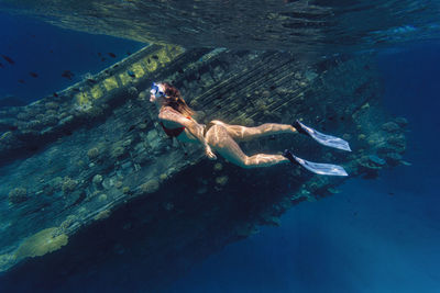 Woman swimming by shipwreck in sea