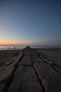 Surface level of walkway by sea against clear sky