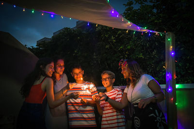 Family burning sparklers while standing in balcony at night