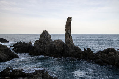 Rock formation on beach against sky