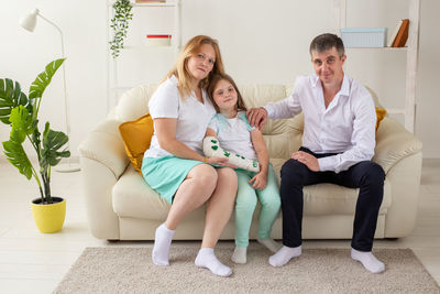 Full length of a smiling young woman sitting on sofa