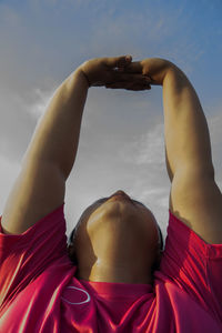 Midsection of woman with arms raised against sky