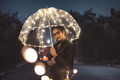 Woman holding illuminated lighting equipment at night