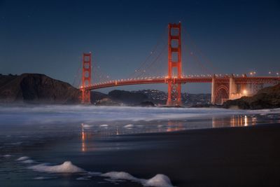 Golden gate bridge over river against sky at night