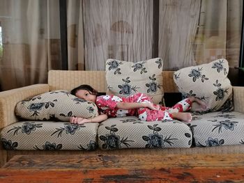 Side view of girl lying on sofa at home