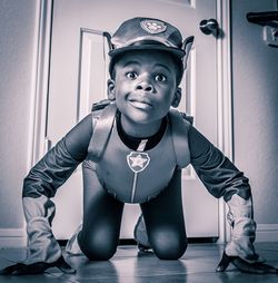 Portrait of boy in superhero costume kneeling on floor