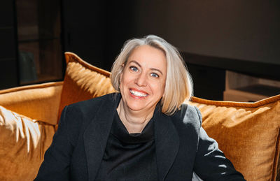 Joyful mature woman with a beaming smile sitting on a velvet sofa