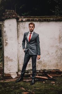 Portrait of young man standing against wall