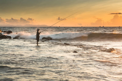 Man standing on beach against sky during sunset