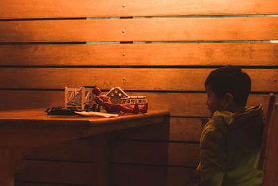 Boy sitting by toys on wooden table