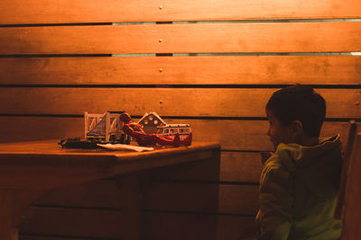 Boy sitting by toys on wooden table
