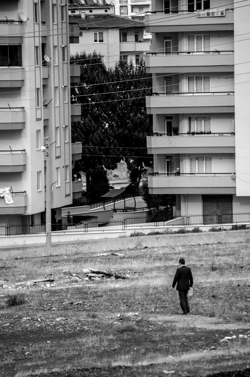 building exterior, architecture, built structure, men, walking, lifestyles, city, full length, person, leisure activity, building, rear view, residential building, city life, street, residential structure, tree, day