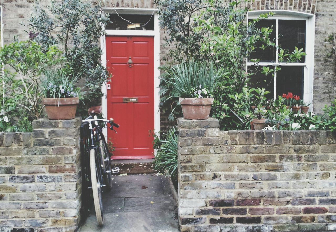 building exterior, built structure, architecture, red, door, house, plant, closed, brick wall, growth, wall - building feature, entrance, wall, potted plant, outdoors, window, day, stone wall, protection, no people