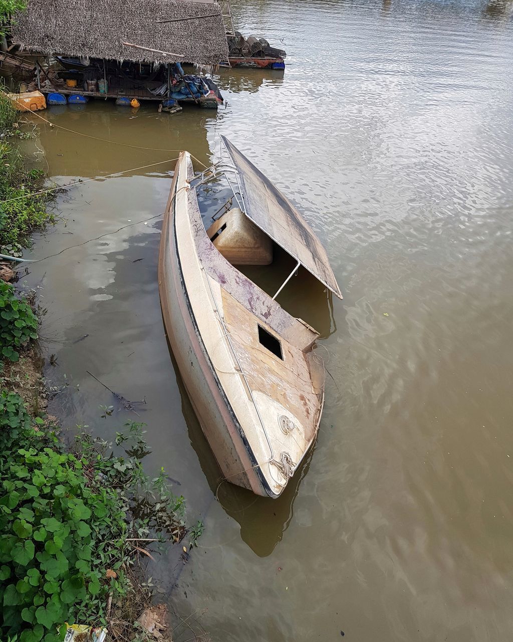 HIGH ANGLE VIEW OF ABANDONED BOAT MOORED AT RIVERBANK