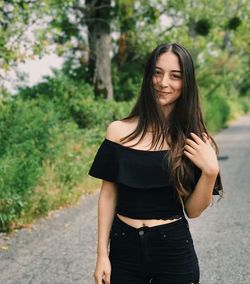 Portrait of young woman standing against trees