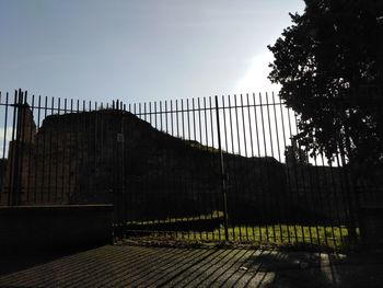 Fence by wall against sky