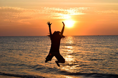 Silhouette woman in sea against sky during sunset
