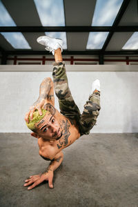 Full body of energetic young man doing acrobatic handstand while performing break dance