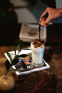Cropped image of hand pouring coffee on table