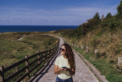 Portrait of woman standing on railing against sky