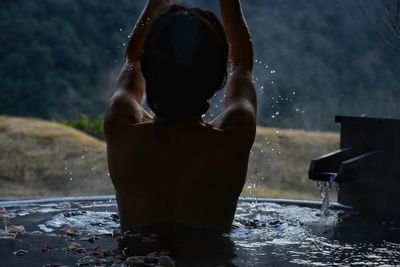 Rear view of shirtless woman in hot spring