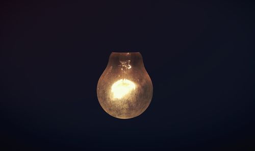 Low angle view of illuminated lamp against black background