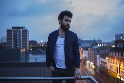 Portrait of a young man standing by railing