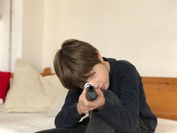Portrait of boy shooting with toy handgun at home