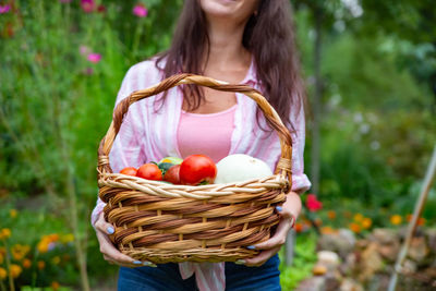 Midsection of woman holding ice cream in basket on field