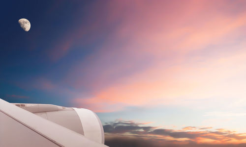 Airplane flying against sky during sunset