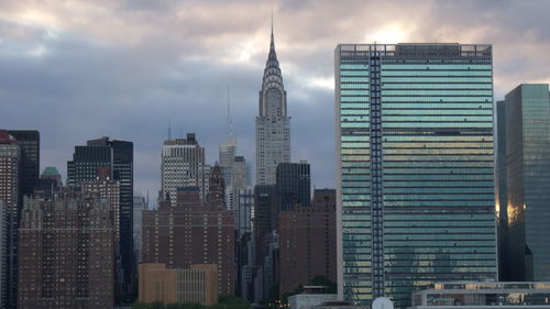 Skyscrapers in city against cloudy sky