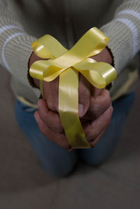 Midsection of person with hands wrapped in ribbons kneeling on floor