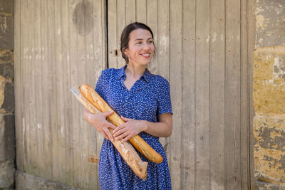 Young woman standing with french baguettes in the countryside