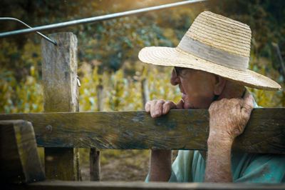 Close-up of senor man wearing hat while standing by railing