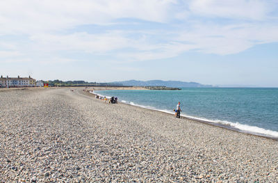 Father with son on shore at beach against sky