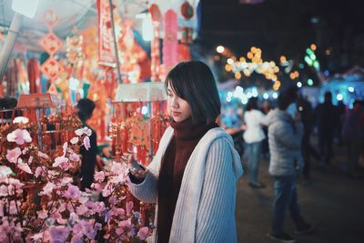 Woman standing in market at night
