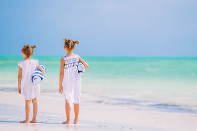 Rear view of women on beach against sky