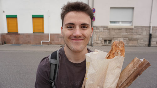 Portrait of smiling man holding ice cream outdoors