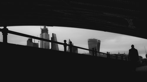 Silhouette people walking on bridge against sky