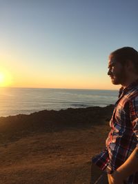 Man looking at sea against sky during sunset