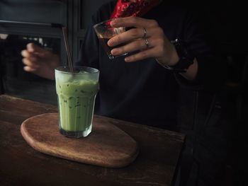 Close-up of hand holding drink on table