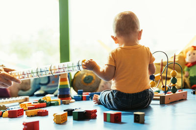 Boy playing with toy sitting on table at home