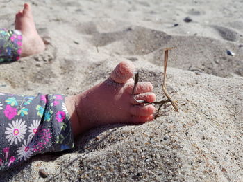 Low section of baby girl sitting on sand at beach