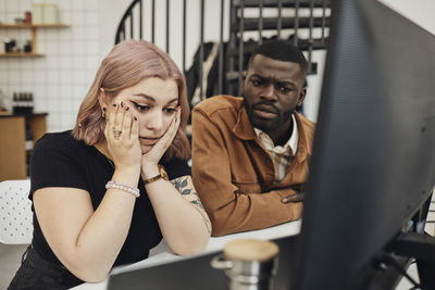Worried businesswoman and businessman looking at computer monitor in office