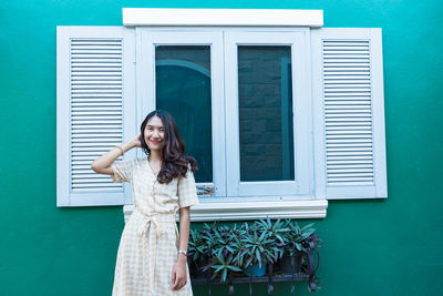 Portrait of woman standing against building