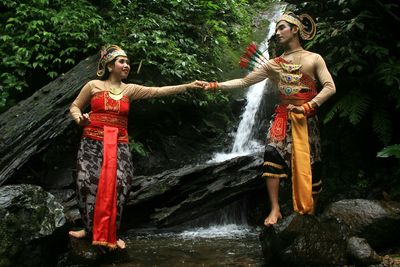 Young couple standing on rock against waterfall