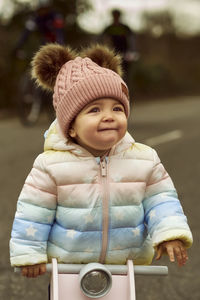 A 1 year old baby girl is with a pink motorcycle outside