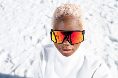 A young african american woman wearing sunglasses having fun in the snow on a winter day